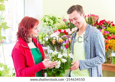 Female florist selling man flowers in flower shop