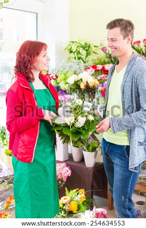 Female florist selling man flowers in flower shop