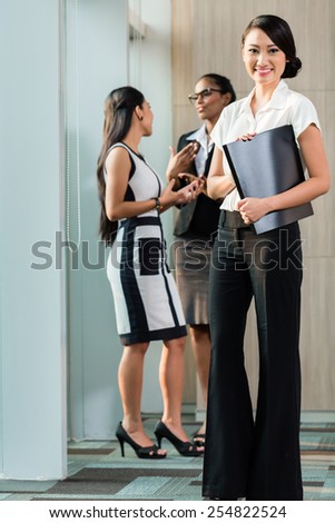 Chinese Business woman standing in front of team