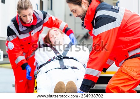 Emergency doctor and nurse or ambulance team transporting accident victim on stretcher