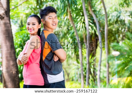 Asian Chinese man and woman take a break after fitness jogging in city park