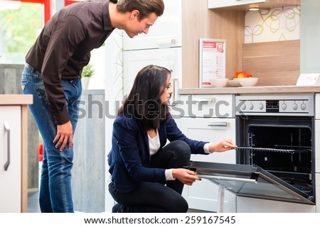 Man and woman buying domestic kitchen in studio or furniture store showroom