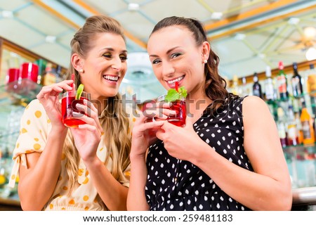 Two women friends in cafe bar drinking long drink or cocktails