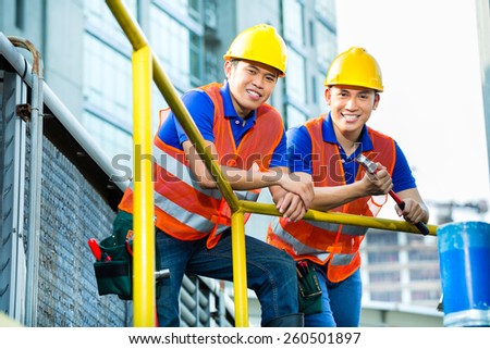 Asian Indonesian construction workers with helmet and safety vest on a building site in Asia