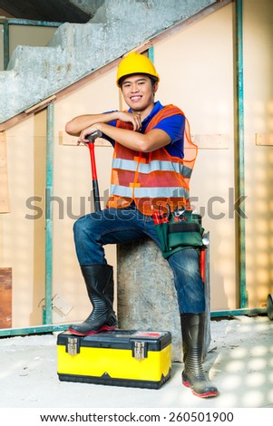 Asian Indonesian construction worker with helmet and safety vest on a building site in Asia