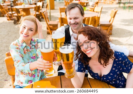 Friends toasting with beer in garden restaurant