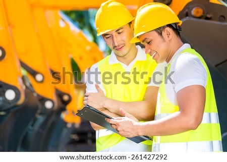 Asian engineer controlling construction machinery of construction site or mining company