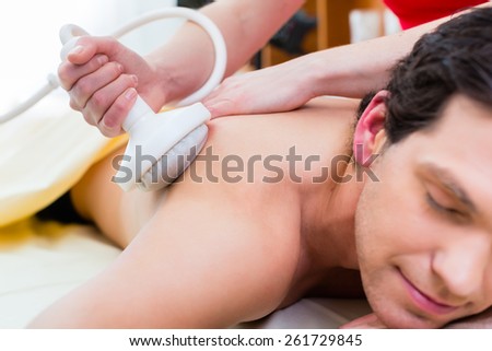 Man having relaxing herbal bag back massage in wellness spa
