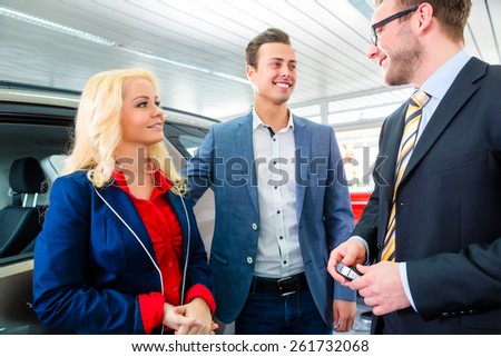 Couple buying car at dealership and consulting salesman