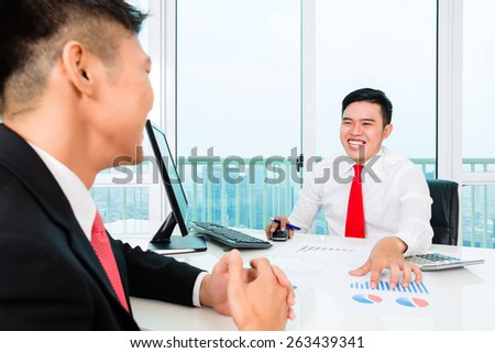 Asian banker offering client finance assets in bank office