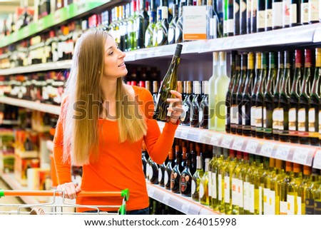 Woman buying wine in supermarket store