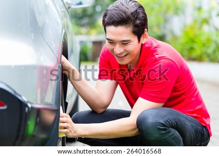 Asian man cleaning car rims with sponge