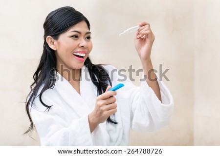 Asian woman being joyfully checking her pregnancy test in the morning