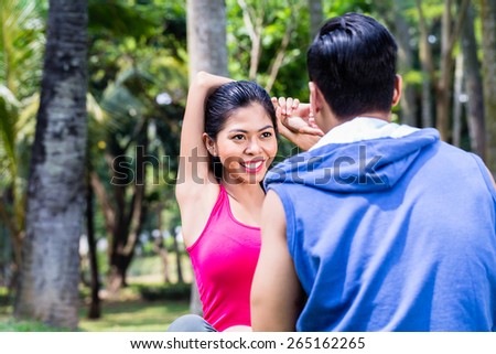 Asian woman and man, a couple, during gymnastics stretching for sport fitness in tropical park