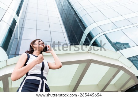 Asian businesswoman telephoning with smartphone in front of tower building