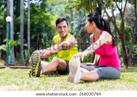 Asian woman and man, a couple, during gymnastics stretching for sport fitness in tropical park