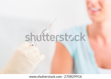 Doctor preparing syringe in practice in front of patient