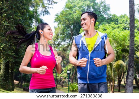 Asian couple, man and woman, jogging or running in tropical Asian park for fitness