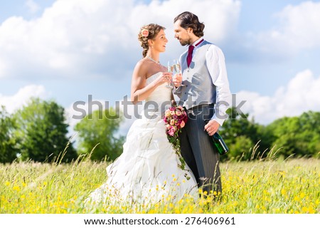 Wedding bride and groom toasting with sparkling wine outside on field