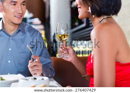Asian couple having dinner and drinking red wine in very fancy restaurant