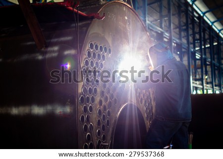 Welder working in an industrial setting manufacturing steel equipment