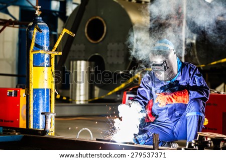 Welder working in an industrial setting manufacturing steel equipment