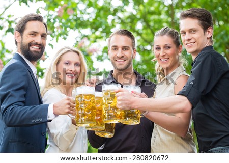 Co-workers after work meeting in beergarden drinking a glass of fresh beer, toasting to the viewer