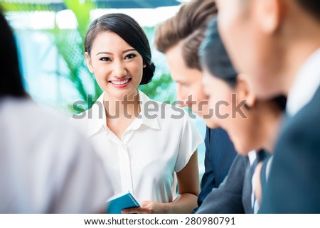 Business team meeting of Asian and Caucasian executives, Chinese woman is looking into the camera