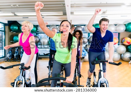 Group of men and women on fitness bikes in gym, diversity people, old, young, black and white