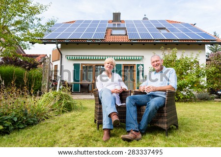 Couple of man and woman sitting in front of their home or house in wicker chairs