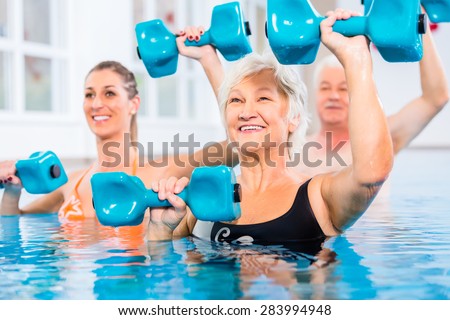 People young and senior in water gymnastics physiotherapy with dumbbells