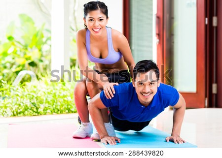 Asian woman helping man with push-up to gain better fitness