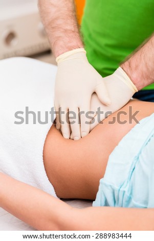 Practitioner at colon therapy massaging abdomen wall of woman