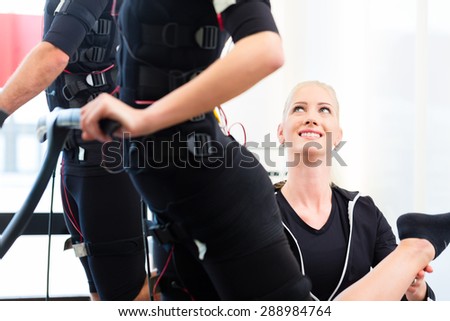 Female coach giving man and woman ems electro muscular stimulation exercise