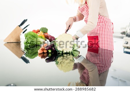 Reflection of Asian woman cooking food in very modern kitchen