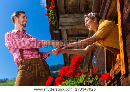 Couple in love at mountain hut window wearing traditional clothing