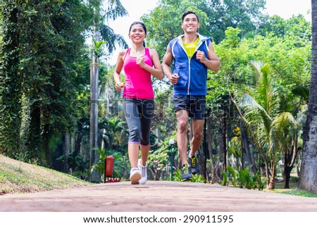 Asian couple, man and woman, jogging or running in tropical Asian park for fitness