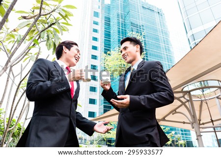 Asian business men having coffee break in front of tower building