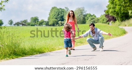 Mom, dad and daughter having walk on path in summer