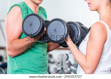 young couple in gym lifting dumbbells in fitness exercise workout