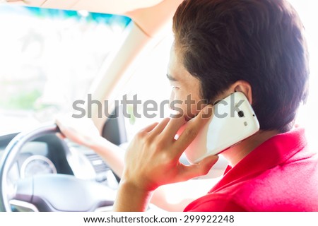 Asian young man telephoning with mobile phone or smartphone while driving car
