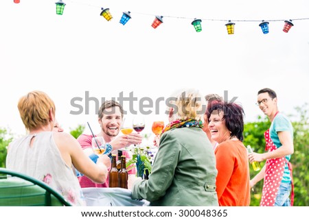 Friends and neighbors on long table celebrating party toasting with drinks