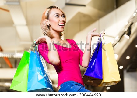 Asian young woman shopping fashion in store with lots of bags over her shoulders
