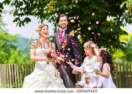 Wedding couple bride and groom with flower children or bridesmaid in white dress and flower baskets
