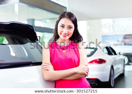 Asian Chinese woman buying SUV car marveling at the beauty of the auto