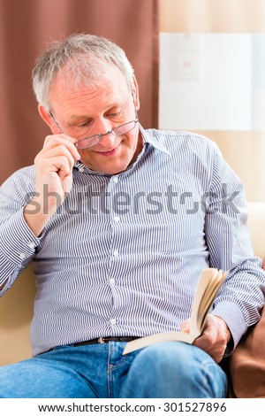 Old man reading  medicament package insert at home with glasses