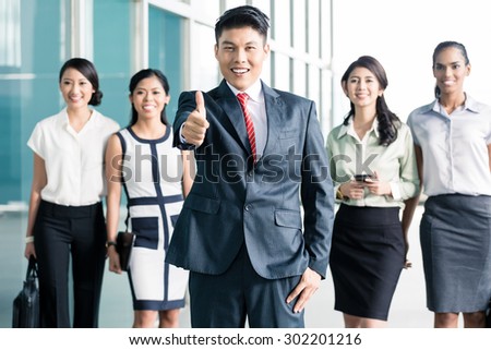 Bank staff in front of Asian office showing thumbs up, men and women of Chinese, Indonesian, and Indian ethnicity