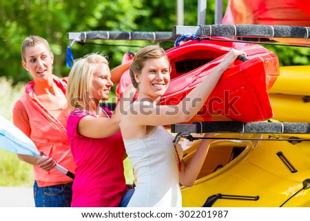 Three women unloading kayak from boat trailer