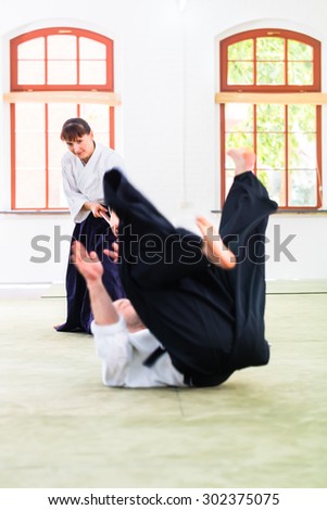 Man and woman fighting with wooden stick at Aikido training in martial arts school