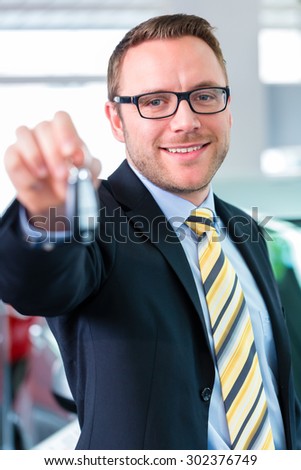 Salesman handing over auto key at car dealership